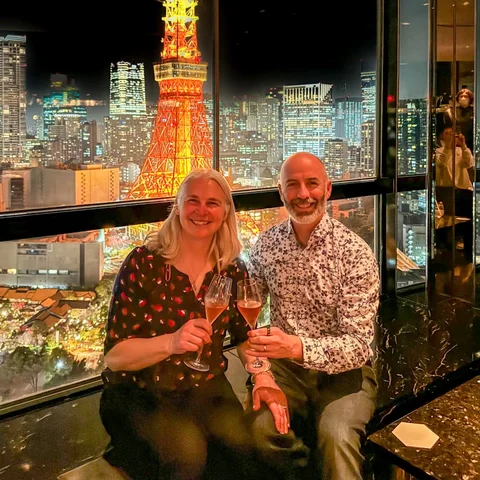 Ben and his wife raising a glass in front of Tokyo Tower at night
