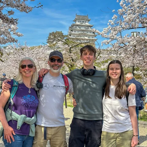 The family together beneath cherry blossom, with a Japanese castle behind them