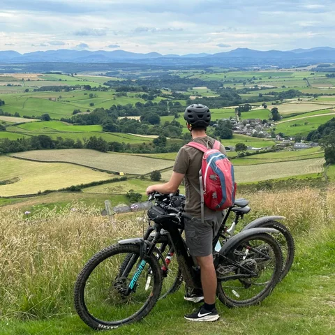 A mountain biker looking out over farmland and distant hills